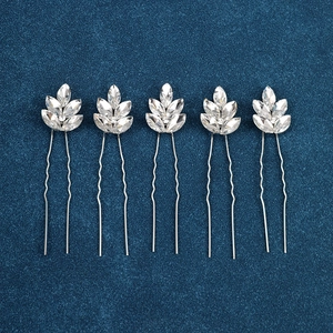 Detail of five silver U-shaped hair pins with marquise rhinestone leaves on navy velvet