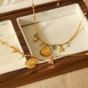 Detail of gold ocean-themed necklace with shell, starfish and turquoise in a wooden box