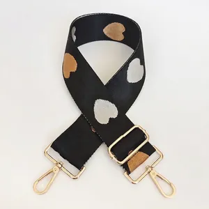 Detailed close-up of a wide nylon bag strap featuring heart patterns and gold lobster clasps