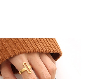 Close-up of a minimalist gold oval cutout ring worn by a model in a brown sweater