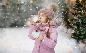 Pink knit cable hat with large brown pom pom for girls in a snowy winter outdoor setting