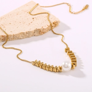 Macro detail of 18k gold plated square beads and white pearl on minimalist necklace