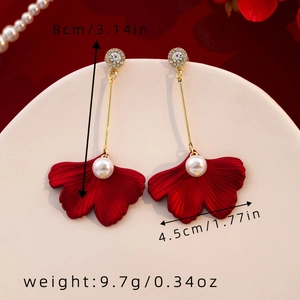 Macro shot showing dimensions of red leaf earrings with pearls and gold hook details