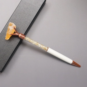 Detailed macro view of a white pen with raw yellow crystal stone and a gift box