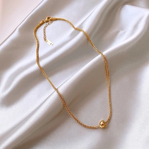 Macro view of gold titanium steel ball pendant necklace on elegant white silk background