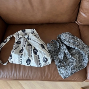 Flat lay of linen tote bags with ethnic floral prints on a brown leather surface