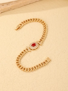 Detail of gold Cuban link bracelet with red oval gemstone and white zircon setting