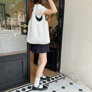 Outdoor shot of a large white canvas tote bag with black polka dots and shoulder straps