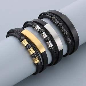 Close-up of braided leather bracelets with stainless steel beads and engraved metal plates