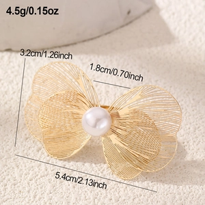 Detailed view of golden butterfly accessory with hollow wings and central pearl inlay