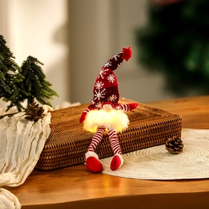 Close-up of a lit Christmas gnome with glowing beard and red snowflake hat on a table