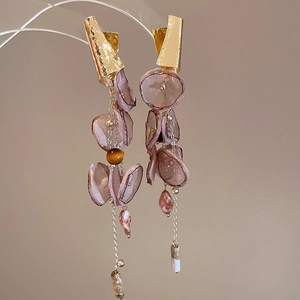 Macro shot of chiffon flower earrings with long tassels and golden metal leaf accents