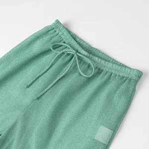 Gros plan d'un pantalon en maille verte scintillante avec taille élastique et cordon