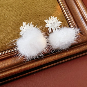 Macro shot of white faux fur pom-pom earrings with silver snowflake zircon details