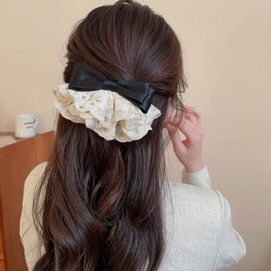 Détail d'une pince à cheveux avec nœud en satin noir et dentelle sur cheveux