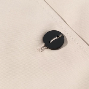 Detail of a black round button on khaki twill fabric with reinforced stitching