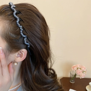 Detail of wavy black headband with clear crystals worn by model for elegant hair styling