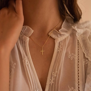 Detailed view of 18K gold stainless steel cross necklace on a person's neckline