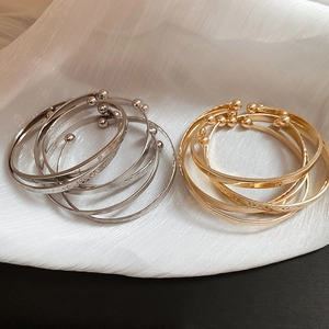 Close-up of gold and silver open bangles with LOVE engraving and bead ends
