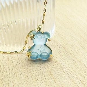 Detail of light blue resin bear pendant with gold starfish charms on a gold chain