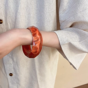 Detail view of acrylic resin bangle with faceted geometric edges and marble texture