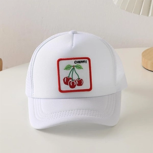 Dettaglio del cappello trucker bianco con toppa a ciliegia ricamata e rete traspirante