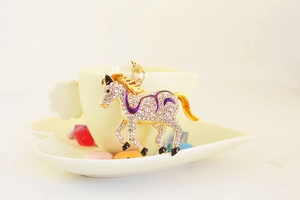 Detailed close-up of golden horse keychain with purple enamel and clear crystals