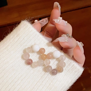 Detail of pink and white beaded elastic bracelet styled against a white sweater sleeve