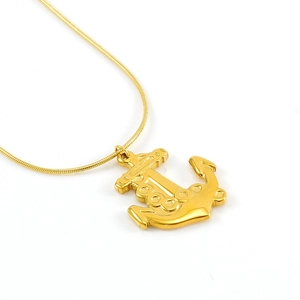 Détail d'un pendentif ancre doré sur une chaîne serpent sur un fond blanc neutre