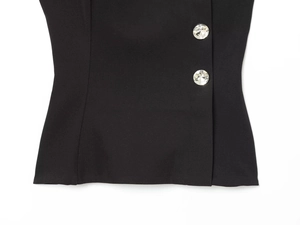 Close-up of black fabric with sparkling crystal buttons on elegant women's top
