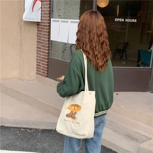 Détail du sac cabas en velours côtelé crème avec broderie mignonne porté à l'épaule