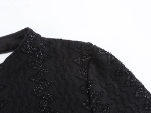 Detail of black tweed dress fabric with sparkling sequins and woven zigzag pattern