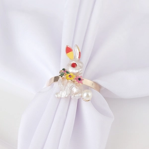 Macro detail of golden bunny napkin ring with white enamel, pearl, and colorful flower accents
