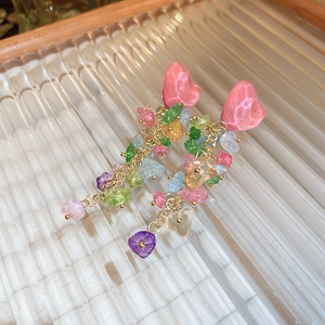 Détail de boucles d'oreilles cœur avec pampilles en cristal coloré sur plateau verre