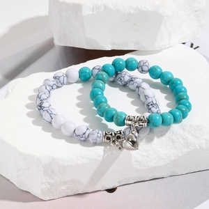 Close-up of magnetic heart pendant on blue and white beaded couple bracelets