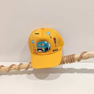 Dettaglio cappellino giallo bimbo con toppa camion blu su un ramo di legno rustico