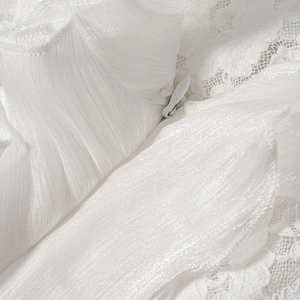 Détail macro de la fermeture éclair invisible sur robe en dentelle blanche plissée