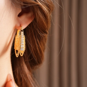 Detail view of gold-plated chain hoop earrings with cubic zirconia on a model