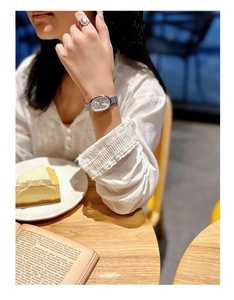 Detail of elegant silver oval quartz watch with mesh band in afternoon tea setting