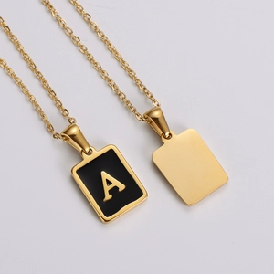 Macro view of gold square letter A pendant necklace with black enamel inlay