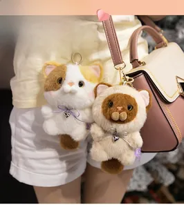 Detail of plush cat keychains with long fur and heart pendants on a trendy bag