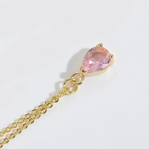 Macro shot of pink waterdrop pendant with gold chain showing fine jewelry craftsmanship