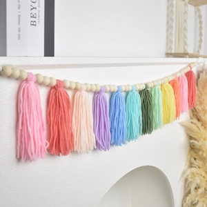 Detail of wooden bead garland with colorful rainbow tassels hanging on white mantel