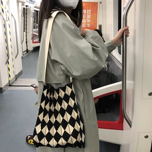 Close-up of black and white checkered knit tote bag used by a person in subway