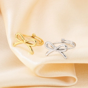 Close-up of gold and silver bow rings on elegant champagne silk fabric background