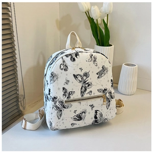 Detail of white backpack with black butterfly prints, gold zippers and side pocket texture