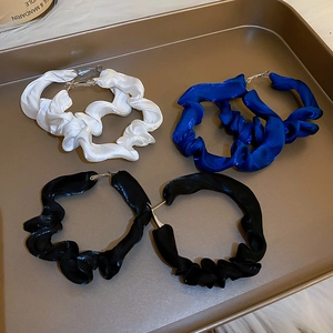 Detail of fabric wrapped hoop earrings in white, blue and black on a gold tray