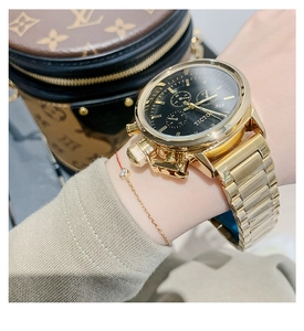Detailed macro of gold steel watch band and black dial with chronograph features