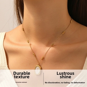 Detailed view of a gold-plated oval pendant featuring floral engraving on a beaded chain
