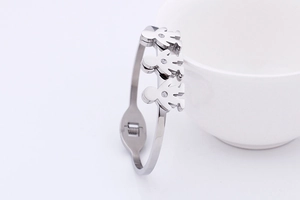 Detail of silver open bangle with three crystal-inlaid figures on white ceramic background